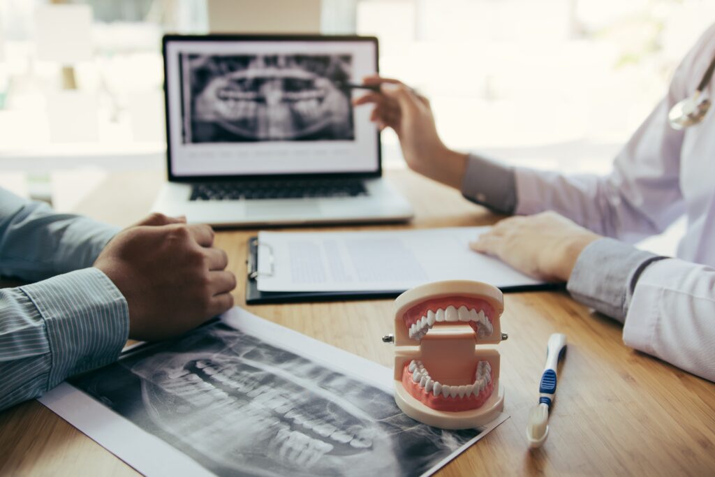 Lakeside smile Dentists are discussing dental problems at report x-ray image on laptop screen to patients.