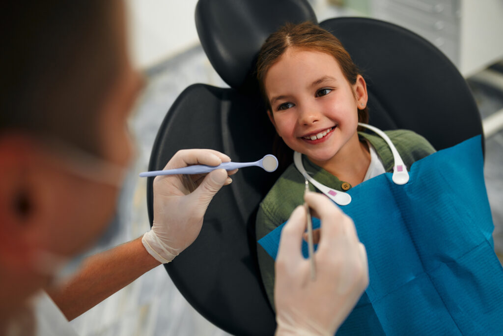Lakeside smile Child little patient sitting on a dental chair smiling on examination at a pediatric dentist. Dentistry and dental care.