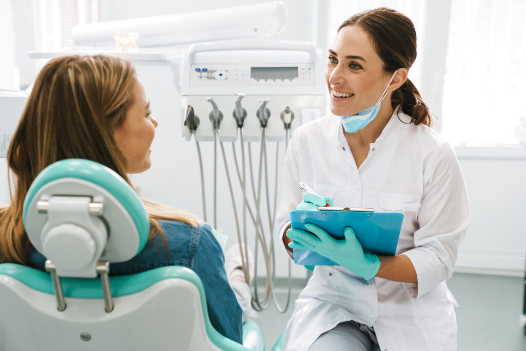 Lakeside smile European mid dentist woman smiling while working with patient in dental clinic discuss Multiple Tooth Extractions.