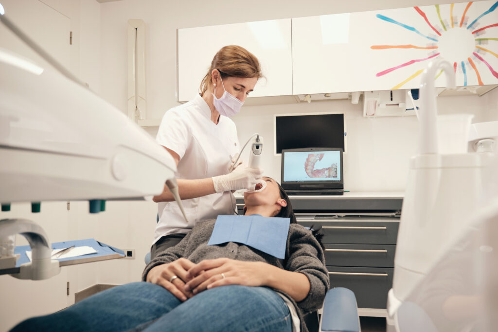 Lakeside smile From above woman in gloves and mask using modern equipment to make scan of teeth of female patient in dentist office