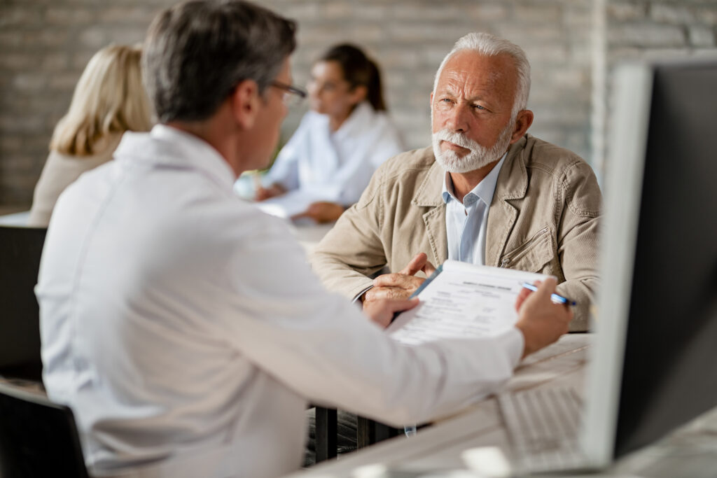 Lakeside smile Mature man and healthcare expert talking about medical records while making health insurance plans at clinic.